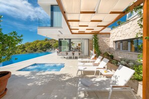 A modern outdoor pool area with lounge chairs, a small pool, and a stone wall with greenery. - Anabel in Hvar With 4 Bedrooms and 4 Bathrooms (Hvar)