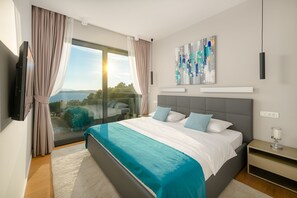 A modern bedroom with a large bed, a TV, a painting, and a view of the outdoors. - Anabel in Hvar With 4 Bedrooms and 4 Bathrooms (Hvar)
