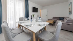 Una sala de estar moderna con comedor, un televisor de pantalla plana montado en la pared y un sofá.