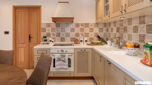 A kitchen with wooden cabinets, a white countertop, and a tiled backsplash. - Ij Dvori in Skradin With 5 Bedrooms and 5 Bathrooms (Skradin)
