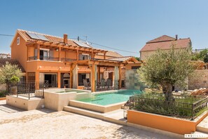 En villa i medelhavsstil med en swimmingpool, utomhusmöbler och en pergola.