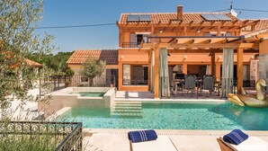 A pool area with lounge chairs, a sun umbrella, and a building with a tiled roof and solar panels. - Ij Dvori in Skradin With 5 Bedrooms and 5 Bathrooms (Skradin)
