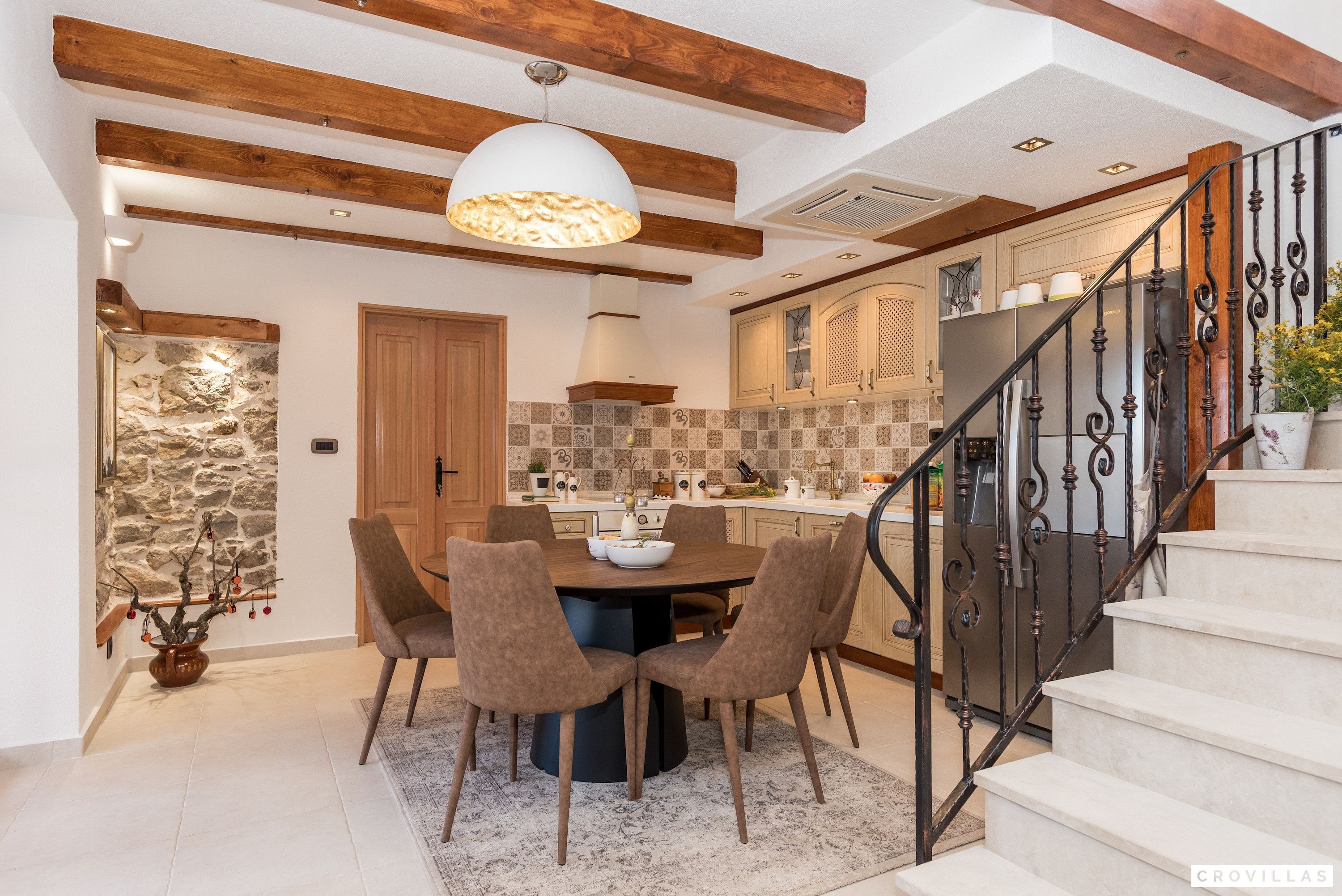 A dining area with a round table, six chairs, and a pendant light.