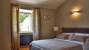 A hotel room with a bed, a nightstand, a lamp, and a window with curtains. - Zita in Jakomi i With 5 Bedrooms and 5 Bathrooms (Pican)
