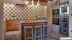 A modern kitchen with a checkered backsplash, wooden bar stools, and a wine fridge. - Zita in Jakomi i With 5 Bedrooms and 5 Bathrooms (Pican)