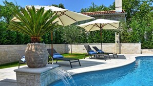 A swimming pool with lounge chairs and umbrellas, a stone wall, and a palm tree. - Zita in Jakomi i With 5 Bedrooms and 5 Bathrooms (Pican)