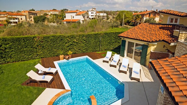 A rectangular swimming pool with a hot tub, surrounded by a wooden deck and lounge chairs. - Santa Domenica in Labinci (Kastelir-Labinci)