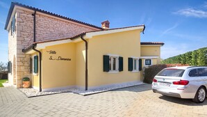 A villa with a stone facade, a yellow exterior, and a parked white car. - Santa Domenica in Labinci (Kastelir-Labinci)