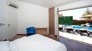 A hotel room with a bed, a desk, a chair, and a view of an outdoor swimming pool. - Santa Domenica in Labinci (Kastelir-Labinci)