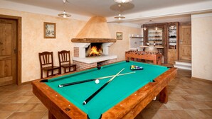 A pool table with a fireplace, chairs, and a foosball table in a room with wooden cabinets and a tiled floor. - Santa Domenica in Labinci (Kastelir-Labinci)