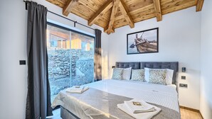 A bedroom with a large bed, a stone wall, and a wooden ceiling. - Lux V in Murter With 2 Bedrooms and 1 Bathrooms (Tisno)