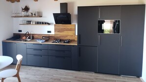 A modern kitchen with dark cabinetry, wooden beams, and a built-in microwave. - Lux V in Murter With 2 Bedrooms and 1 Bathrooms (Tisno)