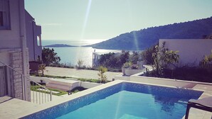 A swimming pool with clear blue water, surrounded by a stone deck and a view of the sea and hills. - Hrvatska in Ra anj With 6 Bedrooms and 3 Bathrooms (Rogoznica)