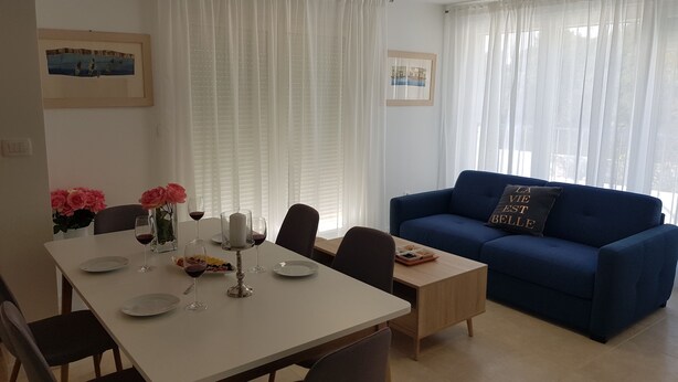 A dining area with a table set for two, a blue sofa, and a small wooden table. - Hrvatska in Ra anj With 6 Bedrooms and 3 Bathrooms (Rogoznica)