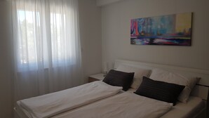 A bedroom with a bed, white curtains, a nightstand, and a painting on the wall. - Hrvatska in Ra anj With 6 Bedrooms and 3 Bathrooms (Rogoznica)