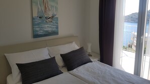 A bedroom with a bed, pillows, a nightstand, a painting of sailboats, and a view of the sea through a window. - Hrvatska in Ra anj With 6 Bedrooms and 3 Bathrooms (Rogoznica)