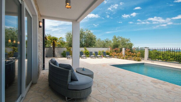 Un espacio al aire libre cubierto con piscina, mobiliario de mimbre y vistas al cielo.