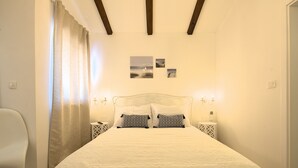 Un dormitorio con cama, mesitas de noche, una silla y una cortina.