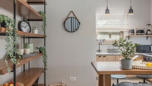Une cuisine moderne avec des étagères en bois, un miroir suspendu et un coin repas comprenant une table et des chaises.
