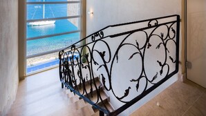 A staircase with a metal railing and a view of the sea through large windows. - Cama in Posedarje With 4 Bedrooms and 2 Bathrooms (Posedarje)