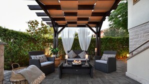 Une terrasse extérieure aménagée avec des meubles en osier, une table basse et une pergola recouverte de tissu.