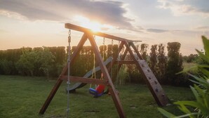 Et legesæt i træ på en græsplæne med en solnedgang i baggrunden.