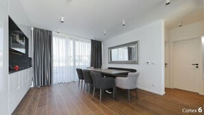 A modern dining area with a wooden table and chairs, a large mirror, and a view of the outdoors through large windows. - K1 in Kraj With 3 Bedrooms and 1 Bathrooms (Pasman)