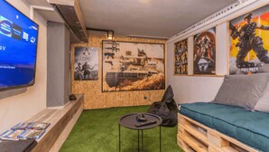 A room with a green artificial turf floor, a wooden bench, a small round table with a remote control, and a wall-mounted television. - La Vrana in Vrana With 3 Bedrooms and 2 Bathrooms (Pakostane)