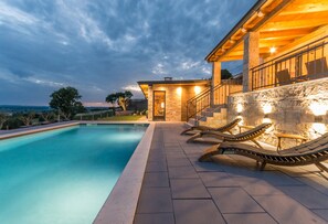 A swimming pool with lounge chairs and a stone building with a balcony. - La Vrana in Vrana With 3 Bedrooms and 2 Bathrooms (Pakostane)