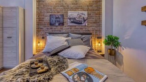 A bedroom with a brick wall, a bed with pillows, a fur throw, a magazine, and a small plant. - La Vrana in Vrana With 3 Bedrooms and 2 Bathrooms (Pakostane)