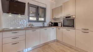 A modern kitchen with white cabinets, a stainless steel oven, and a window with blinds. - La Vrana in Vrana With 3 Bedrooms and 2 Bathrooms (Pakostane)