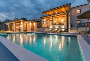 A swimming pool with a sunlit deck area, stone walls, and a covered seating area with lounge chairs. - La Vrana in Vrana With 3 Bedrooms and 2 Bathrooms (Pakostane)