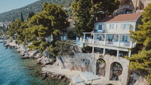 A coastal building with a stone staircase leading to a terrace, overlooking clear blue waters. - Meys Place in Dubrovnik (Dubrovnik)