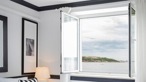 A hotel room with a large bed, a nightstand with a lamp, a window with a view of the sea, and a framed picture on the wall. - Meys Place in Dubrovnik (Dubrovnik)