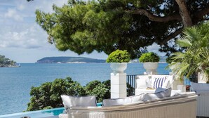 A seaside lounge area with a wicker sofa, a small round table, and a view of the sea. - Meys Place in Dubrovnik (Dubrovnik)