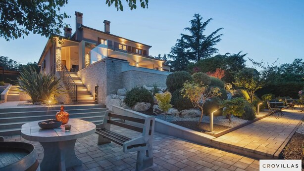 A modern house with a stone facade, a staircase leading to the upper floor, and a well-lit outdoor area with a bench and table. - Terra Labin in Labin (Labin)