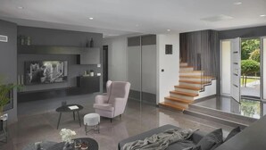 A modern living room with a sofa, armchair, coffee table, and a staircase leading to a balcony. - Terra Labin in Labin (Labin)