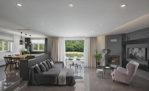 Ein modernes Wohnzimmer mit einer Couch, einem rosa Sessel und einem Essbereich mit Tisch und Stühlen.