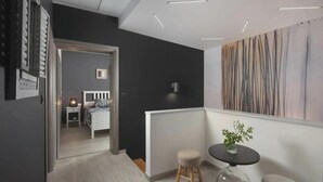 A modern hotel room with a bed, bedside table, lamp, and a view into the adjacent room. - Terra Labin in Labin (Labin)