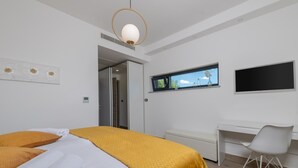 A modern hotel room with a bed, a desk, a chair, a TV, and a window with a view. - Callista in Ru i i (Sveta Nedelja)
