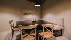 A dining area with a black table, four wooden chairs, a grey sofa, and a wall-mounted light fixture. - Vista Hills in Mo Enice (Moscenicka Draga)