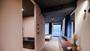 A modern hotel room with a large bed, a small seating area, a view of the sea, and a potted plant. - Vista Hills in Mo Enice (Moscenicka Draga)
