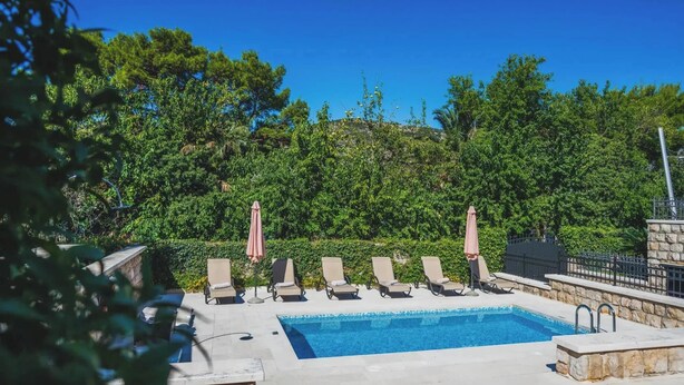 A pool area with lounge chairs and umbrellas, surrounded by dense greenery. - Franica in Dubrovnik (Dubrovnik)