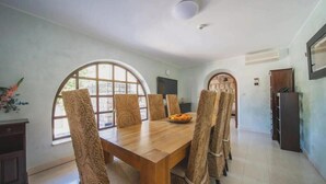 A dining area with a wooden table and six chairs, large arched windows, and a television on the wall. - Franica in Dubrovnik (Dubrovnik)