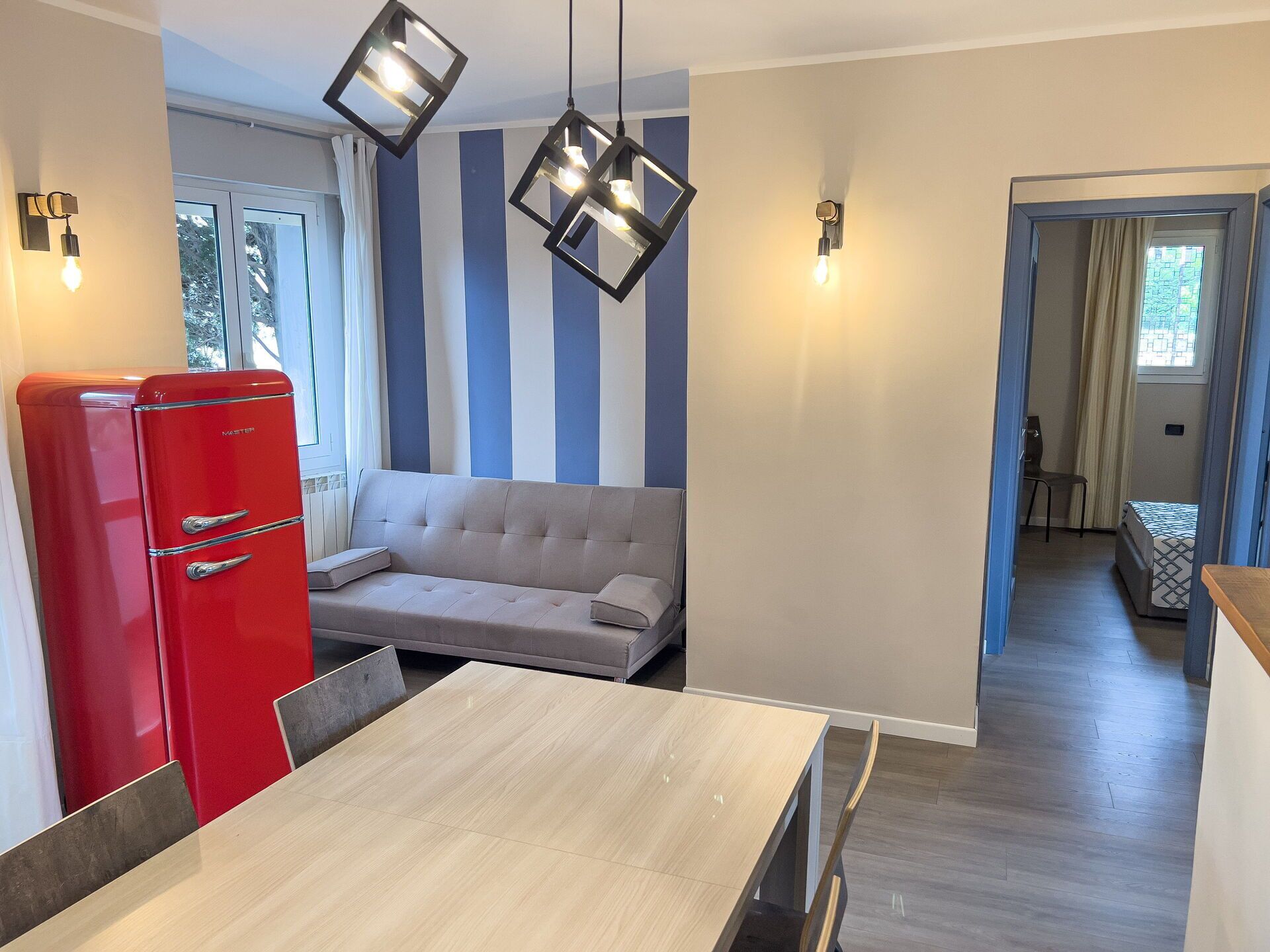 Une cuisine moderne avec un réfrigérateur rouge, un canapé beige et une table à manger.