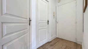 Un couloir avec des portes blanches et un plancher en bois.