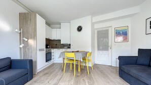 Un appartement moderne comprenant une cuisine, un coin repas et deux canapés.
