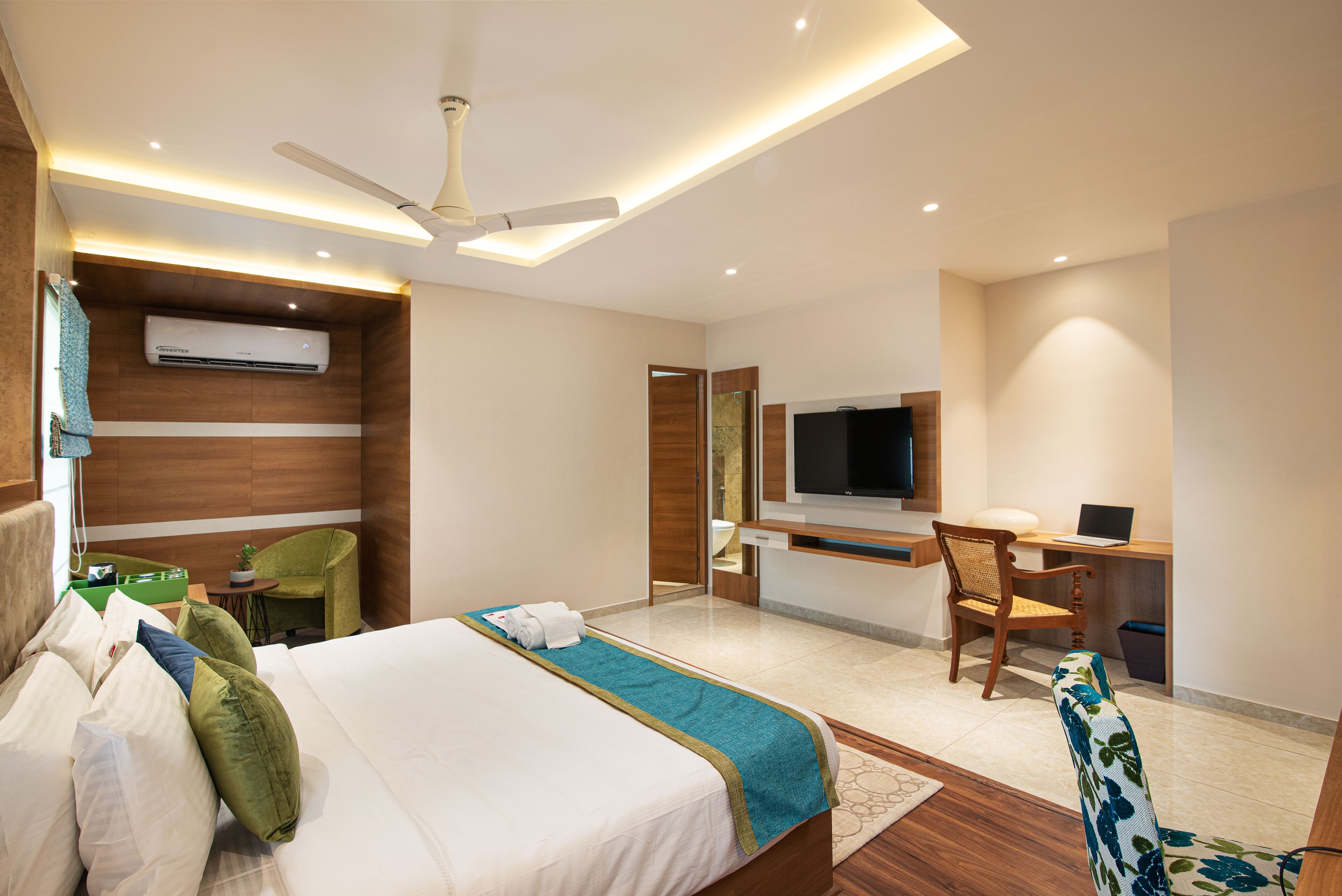 Een hotelkamer met een bed, bureau, stoel, televisie en airconditioning.