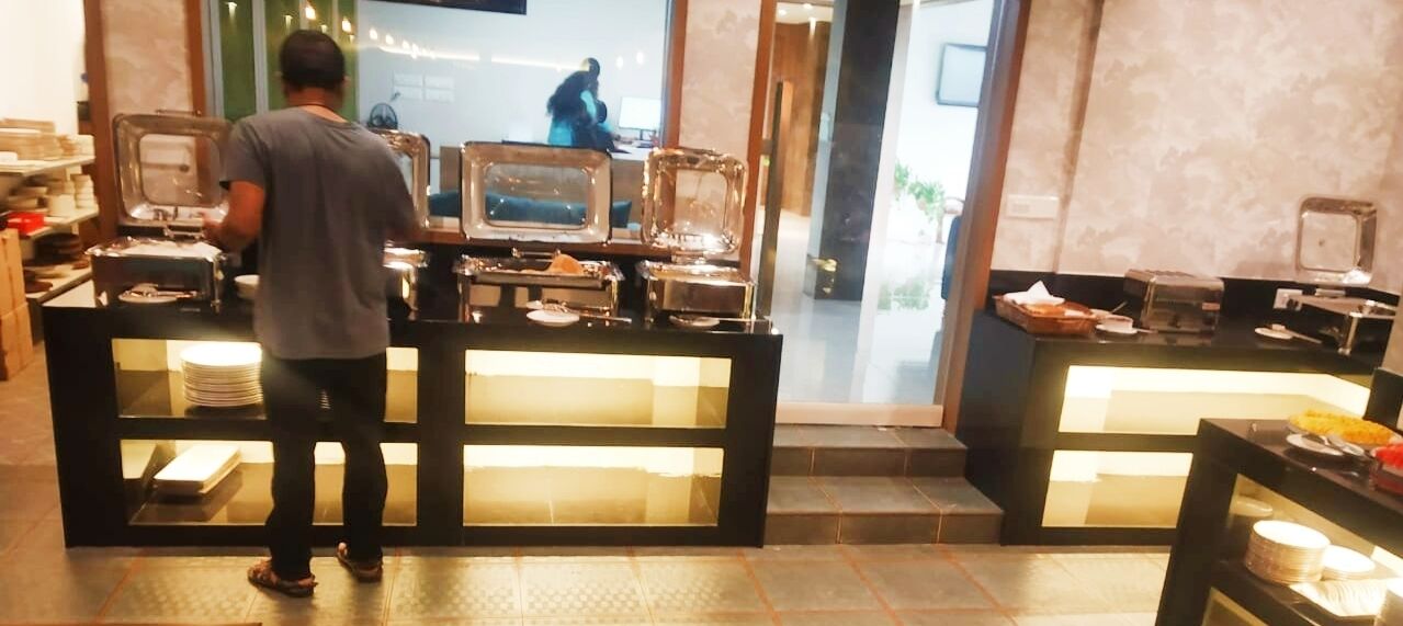 A buffet setup with multiple serving stations, a person serving food, and a counter with various dishes.