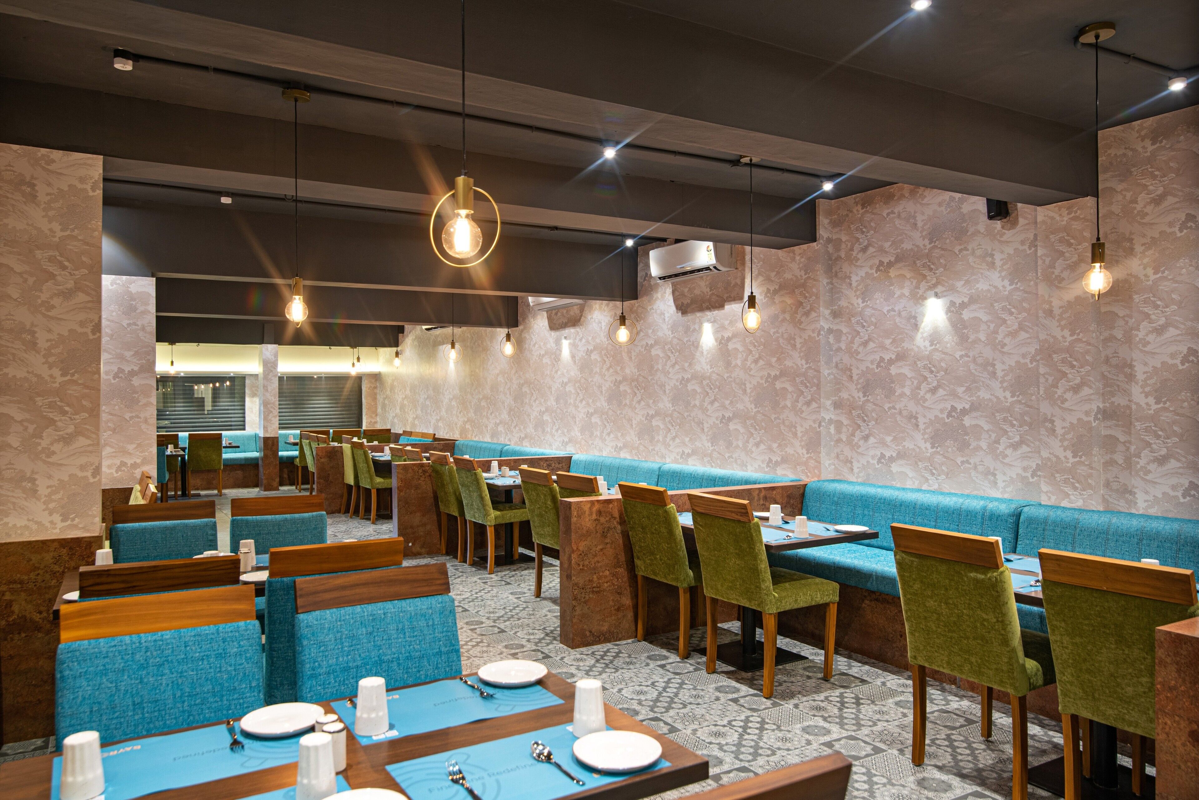 A restaurant with booths and tables, some with blue cushions, and a patterned carpet.